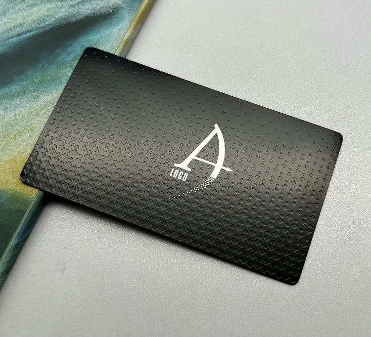 Dette metal visitkort viser et sort teksturmønster med monogramlogo til moderne eksklusiv branding.