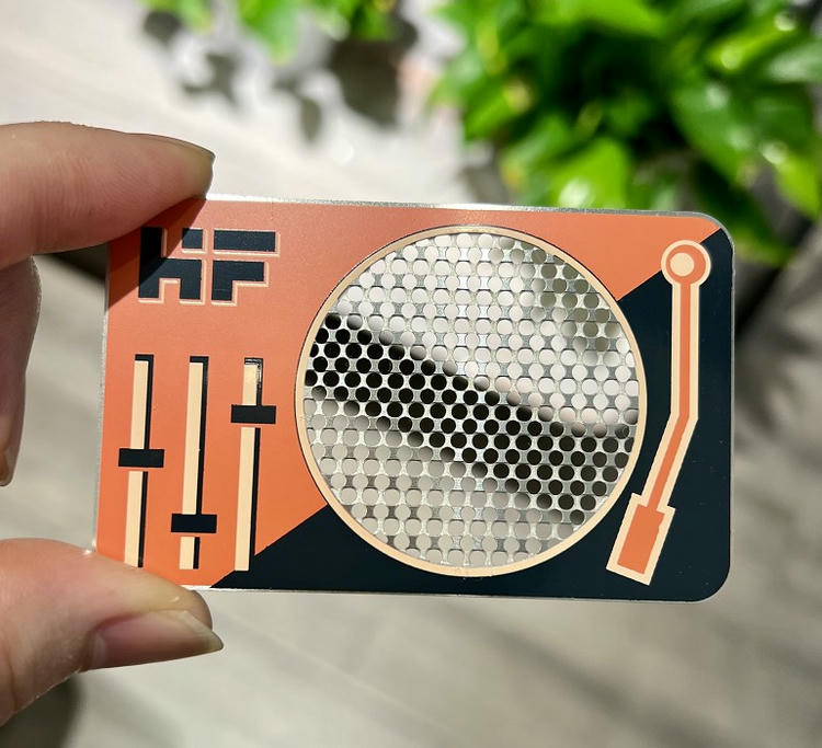 Dette metal visitkort har et orange grafisk design med rundt udskåret felt til markant VIP-identifikation.