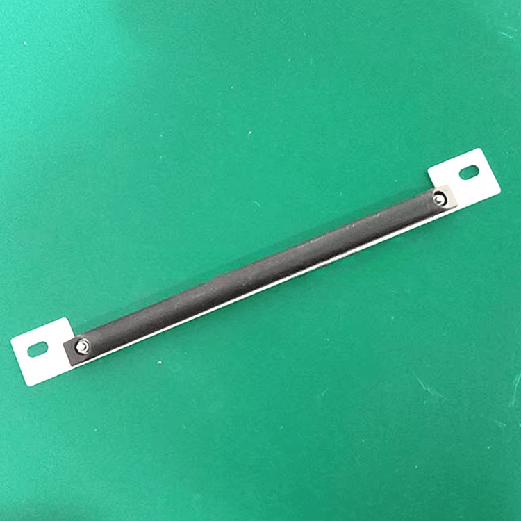 Et enkelt RFID-tag til metal ligger diagonalt på en grøn flade og viser det lange sorte hus med metalflige til parkeringsadgang.