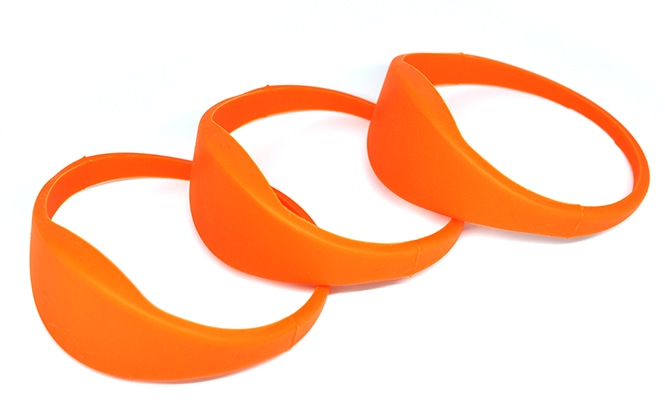 Skrå visning af tre orange G03B silikone RFID-armbånd, der viser det fleksible silikonemateriale og designet med flad kant.