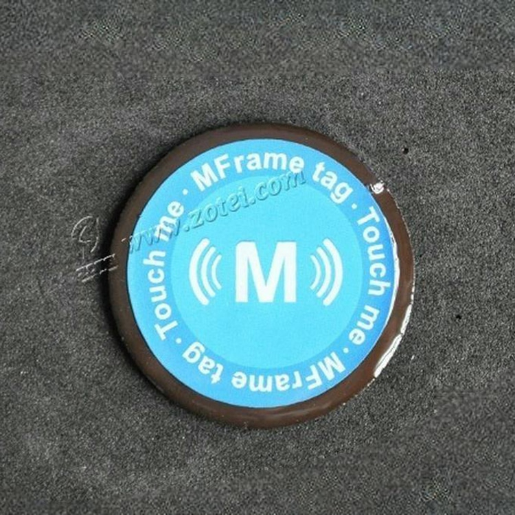 En prøve på et D40mm epoxy-metalresistent RFID-tag vises som et enkelt cirkulært blåt tag på en mørk baggrund med trykt kontaktløs grafik.